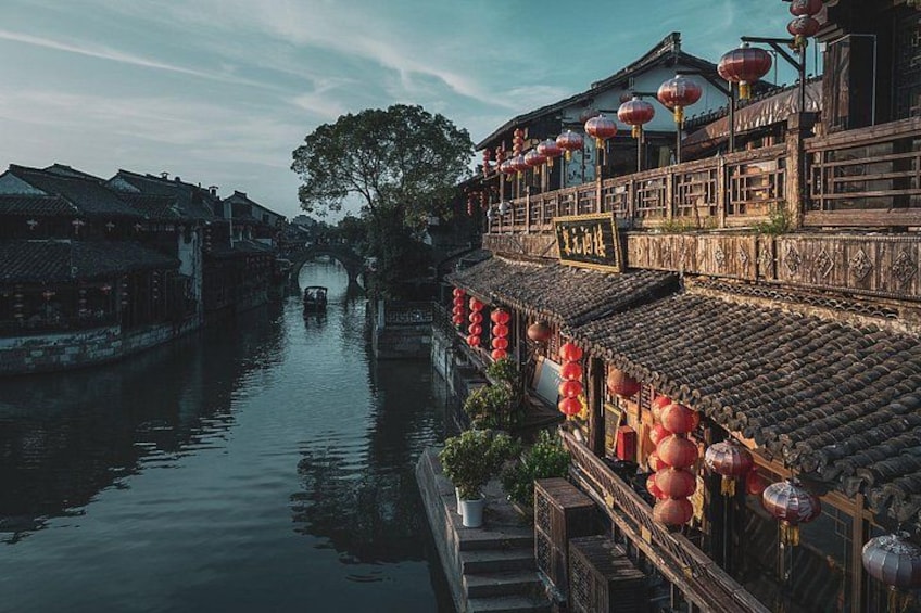 A traditional Chinese water town with wooden buildings, a canal, and red lanterns. 1