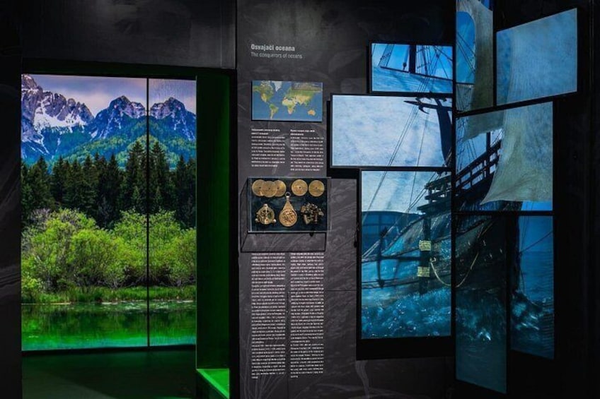 A museum exhibit with a mountainous landscape, a ship, and informational panels. 1