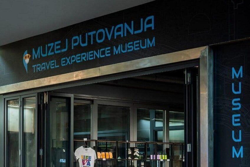 The exterior of the Muzej Putovanja Travel Experience Museum with a sign above the entrance and a display of items inside. 5