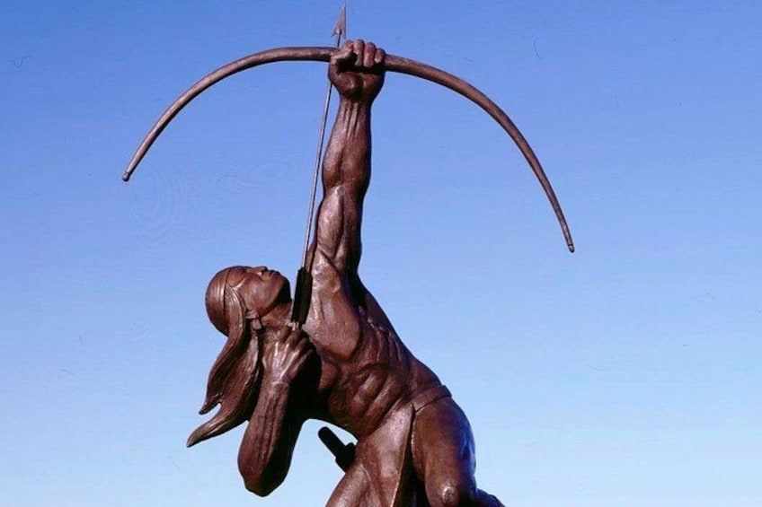 Una estatua de bronce de una figura con arco y flecha, sobre un cielo azul despejado. 4