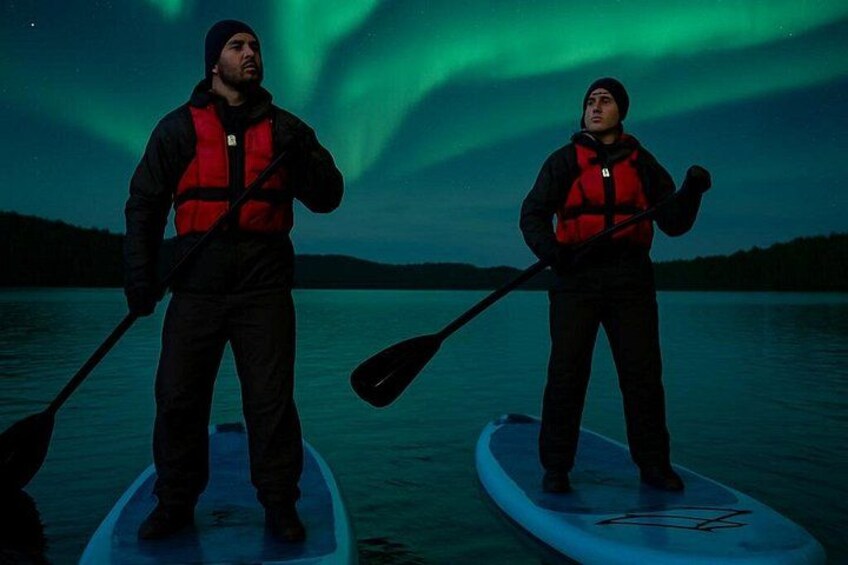 To personer på paddleboards i vandet, med nordlys i baggrunden. 3