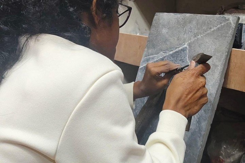 Una persona trabajando en una losa de piedra, posiblemente tallando o esculpiendo. 2
