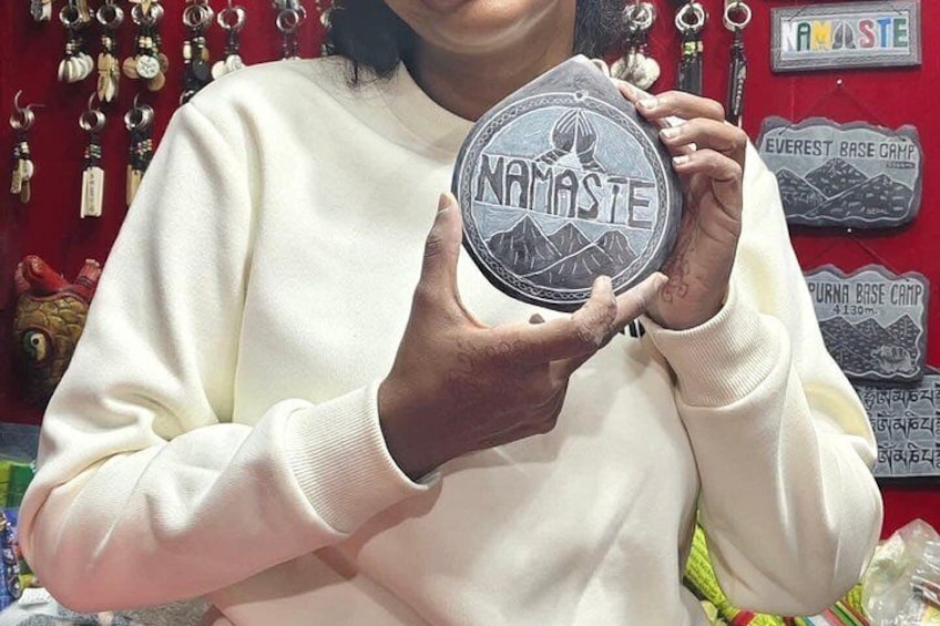 En person håller i ett runt föremål med ordet ”NAMASTE” skrivet på det. 2