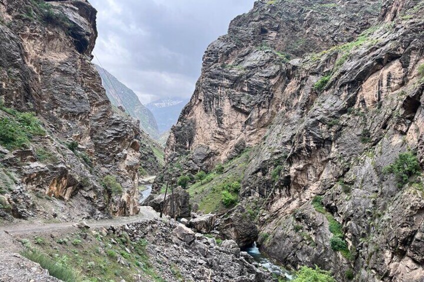 A canyon with steep rocky cliffs and a narrow stream. 5