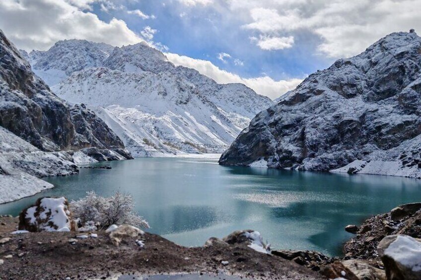 A snow-covered mountain lake with rocky terrain and clear blue water. 2
