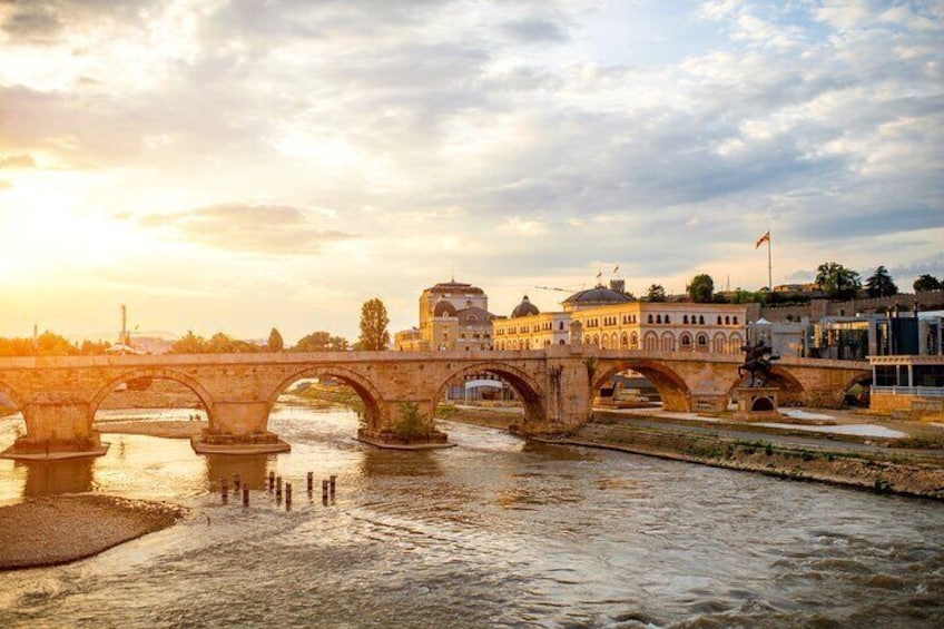 A stone bridge over a river, a historic building, and a clear sky. 5