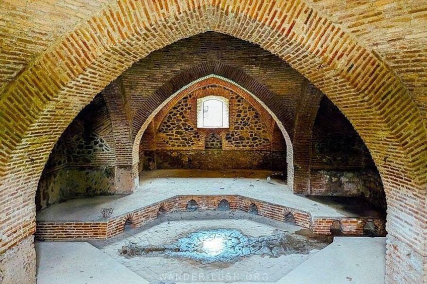 An arched brick structure with a central window and a circular stone feature. 2
