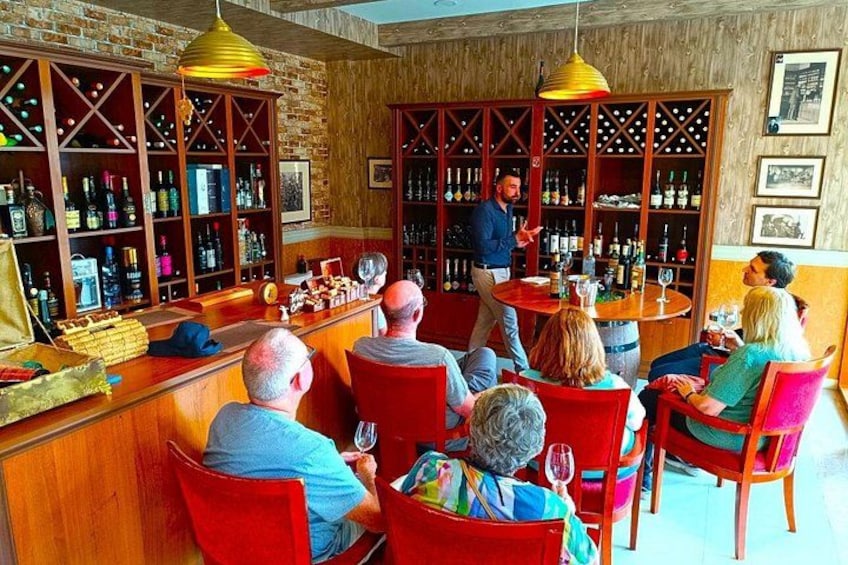 A bar with wooden shelves stocked with bottles, a bartender, and seated patrons. 5