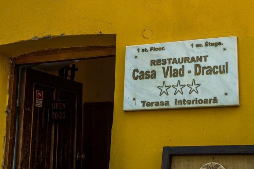A yellow building with a sign for 'Casa Vlad - Dracula' restaurant on the 1st floor. 4
