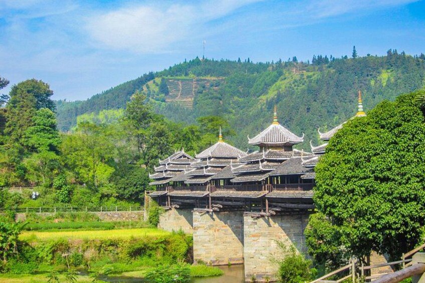 A traditional Chinese building with multiple tiers and golden roofs, surrounded by lush greenery and hills. 2