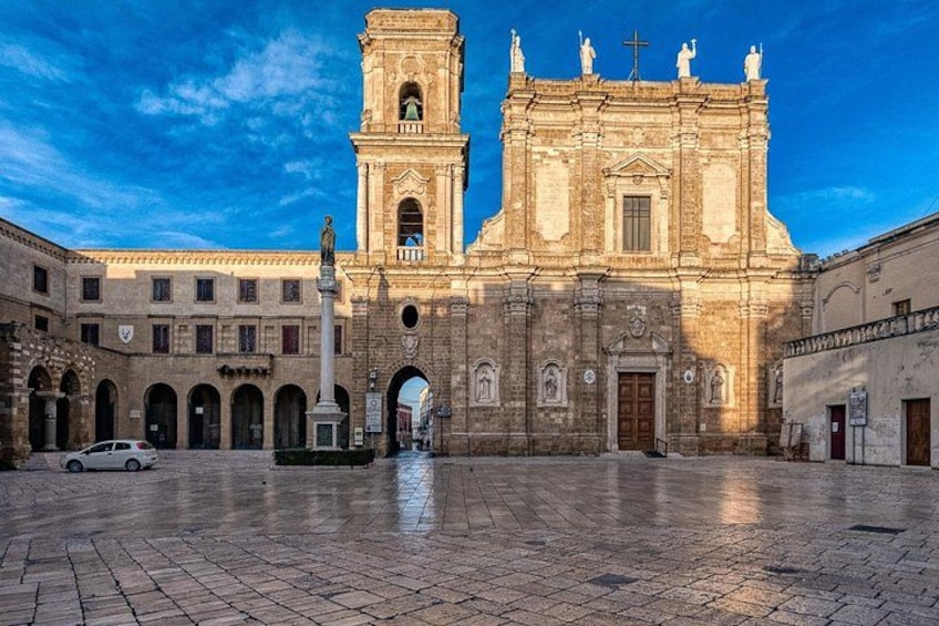Une place historique, dominée par une église remarquable, avec un clocher et des statues, et entourée d’édifices d’architecture classique. 4