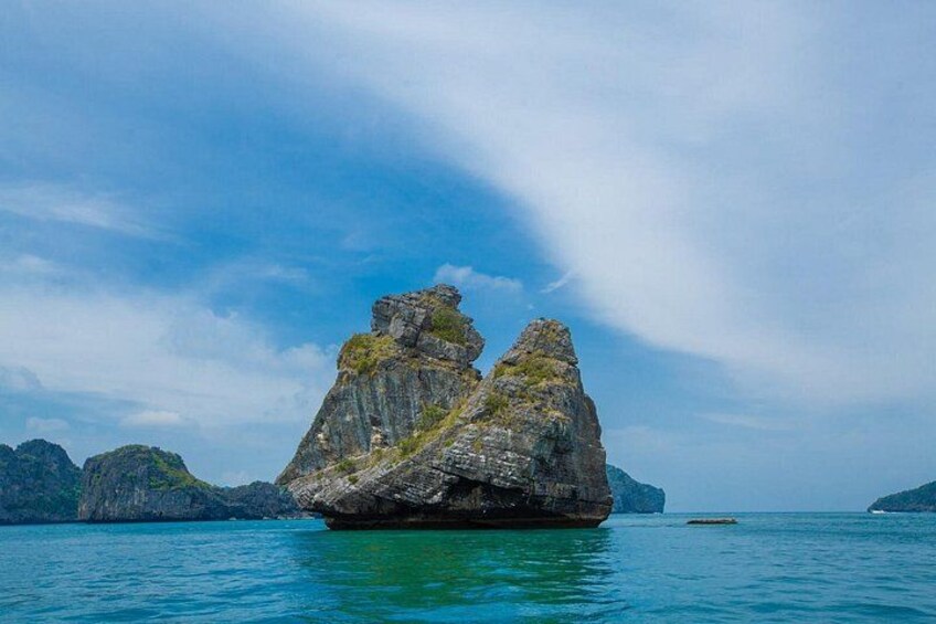 Eine große Felsformation im Meer mit klarem, blauem Wasser und weiter Küstenlinie. 4