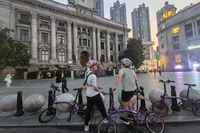 Una persona caminando con una bicicleta frente a un edificio clásico con columnas. 1