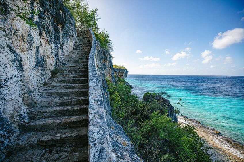 A stone staircase leading down to a beach with turquoise water. 2