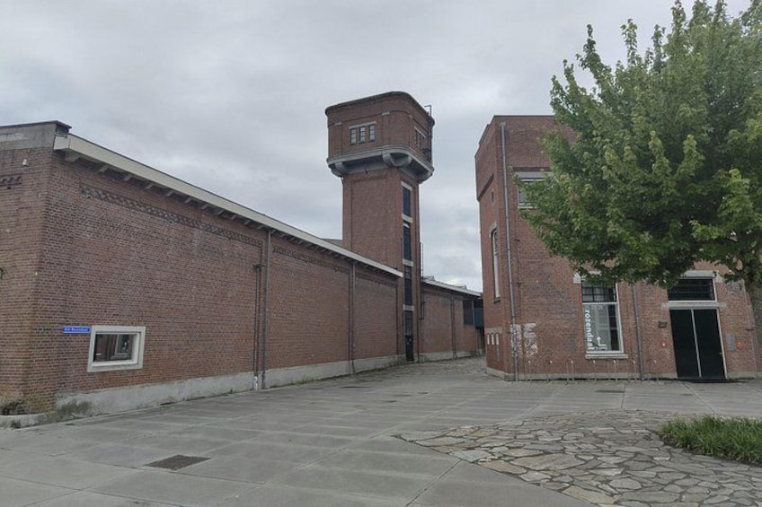A brick building with a tower, a paved walkway, and a tree. 5