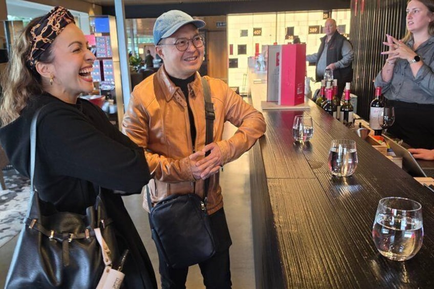 Eine Bar mit Weingläsern und stehenden Gästen. 1