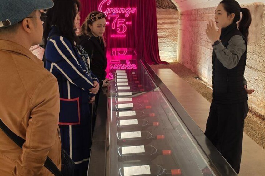 Eine Gruppe von Menschen steht vor einer Vitrine mit einem Neon-Schild, auf dem 'Orange 75' steht. 3