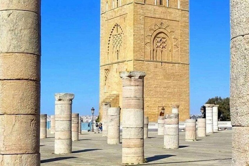 Ancient stone columns, a large brick tower, and a clear blue sky. 5