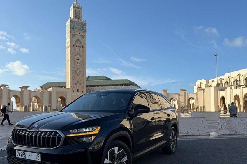 A black SUV parked in front of a historic building with a tall minaret. 1