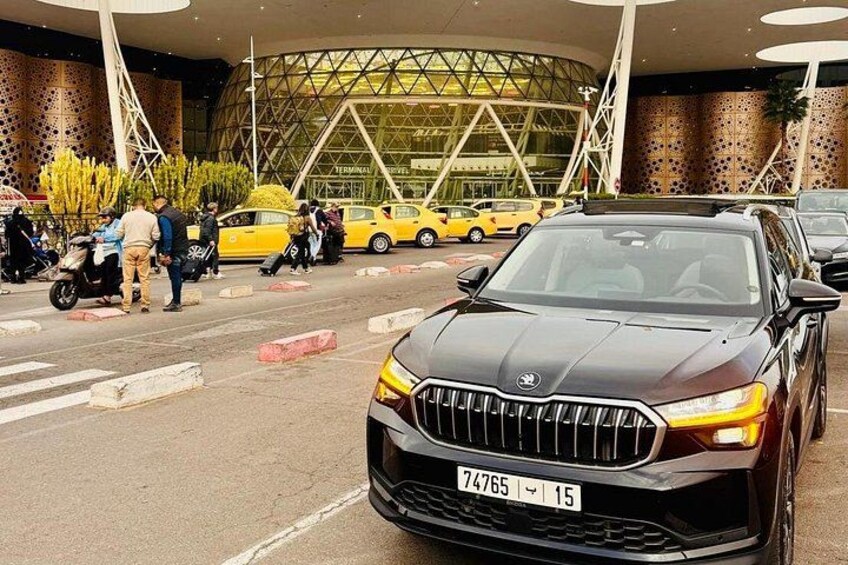 A black car parked in front of a modern building with a glass facade. 3