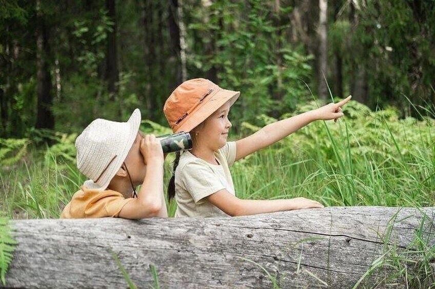 Two children sitting on a log in a forest. 1