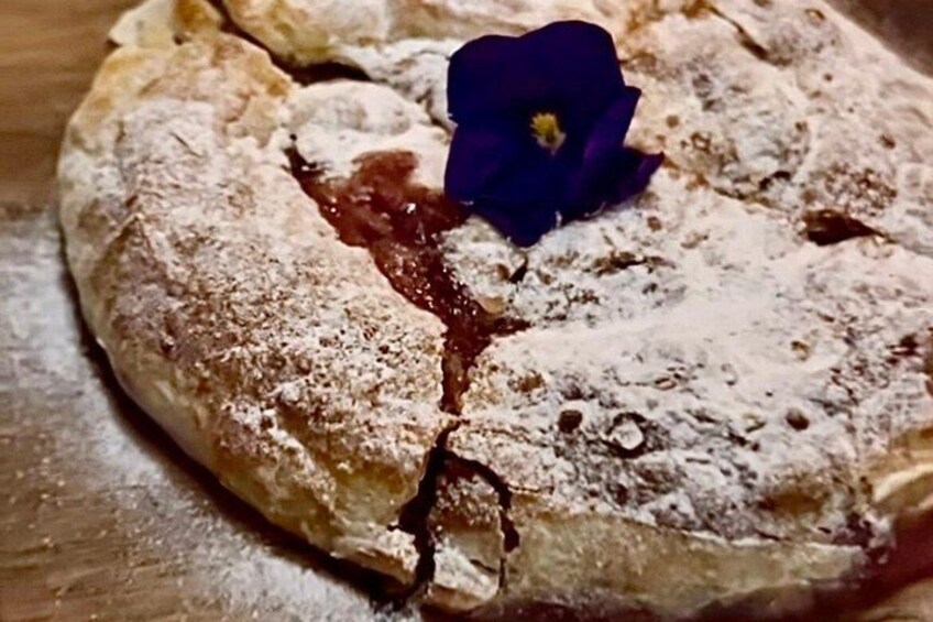 A pastry with powdered sugar and a flower on top. 5