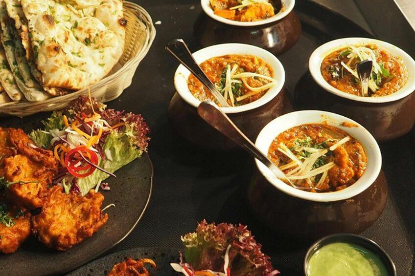 Verschiedene indische Gerichte, darunter Naan-Brot, Curry und ein Salat. 3