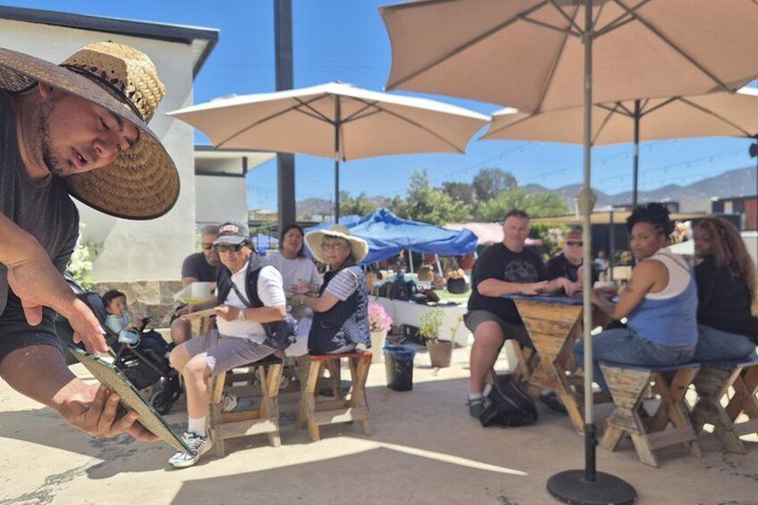 People sitting at wooden tables under umbrellas, outdoors. 5