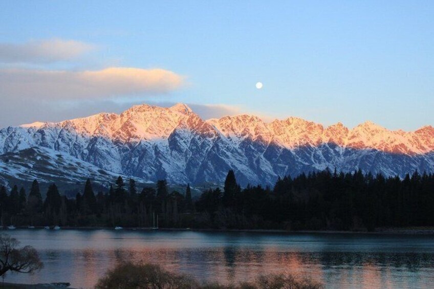 Snow-covered mountains, a calm lake, and a visible moon. 2