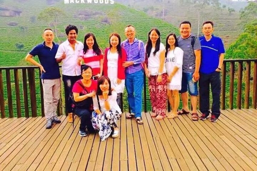 Un gruppo di persone su un pontile di legno con un paesaggio collinare sullo sfondo. 2