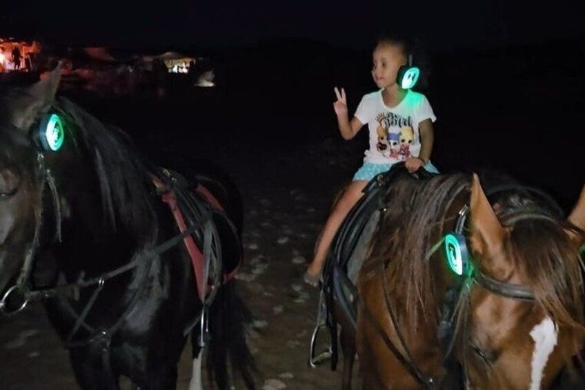 A child riding a horse at night. 2