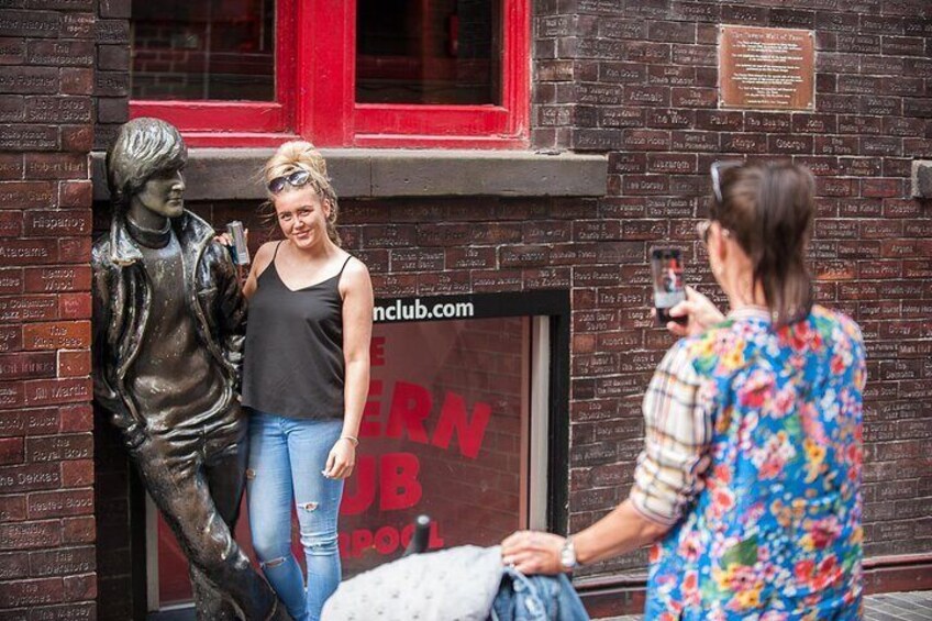 A person taking a photo of a statue and a building with a red sign. 5
