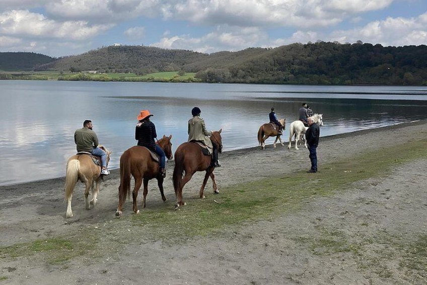 Folk rider heste langs en sti ved søen. 1