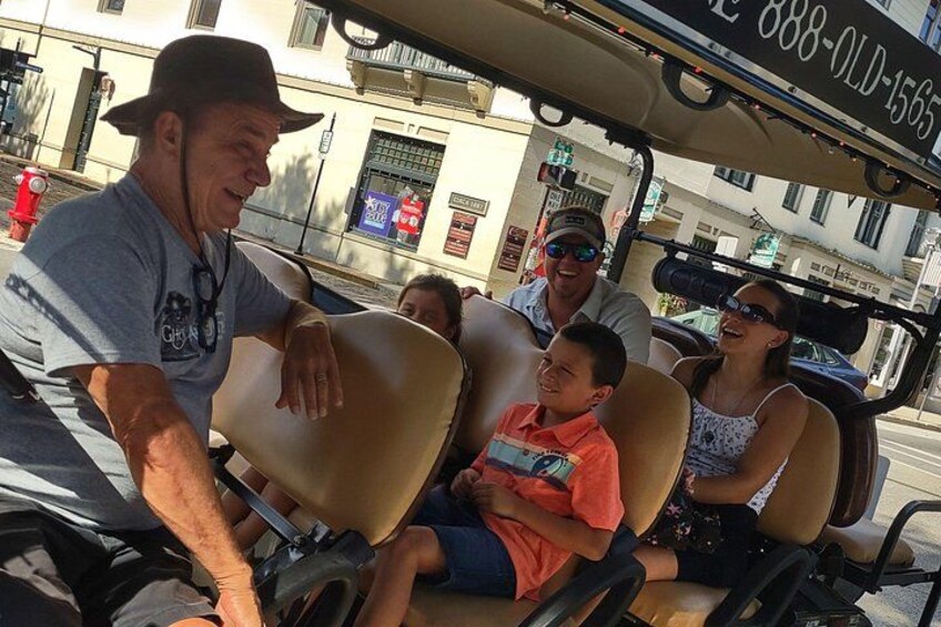 Un grupo de personas en un carrito de golf por una calle. 1