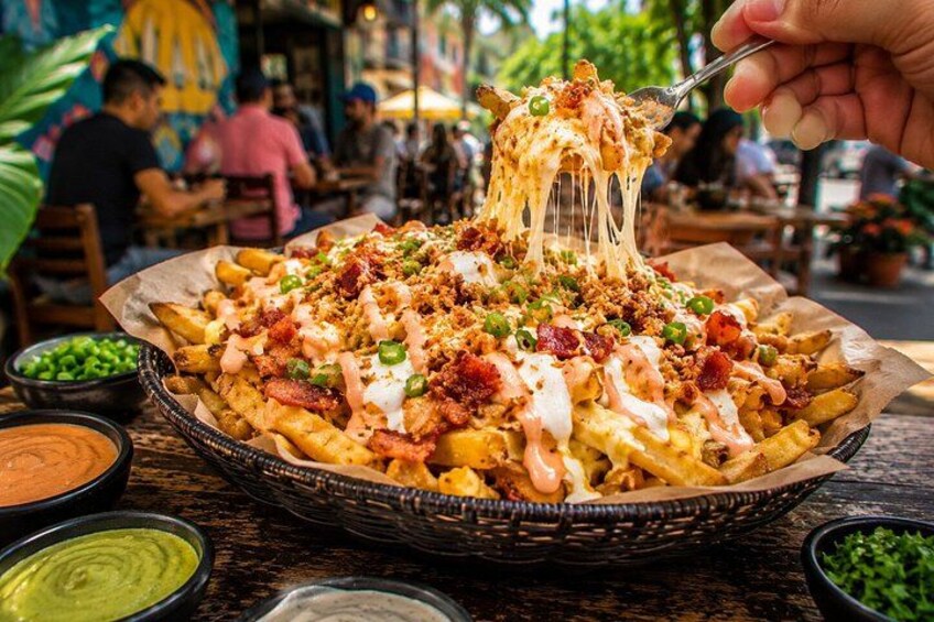 En kurv med pommes frites overdækket med ost, bacon og grønne peberfrugter, samt tilhørende dyppeksaucer. 4