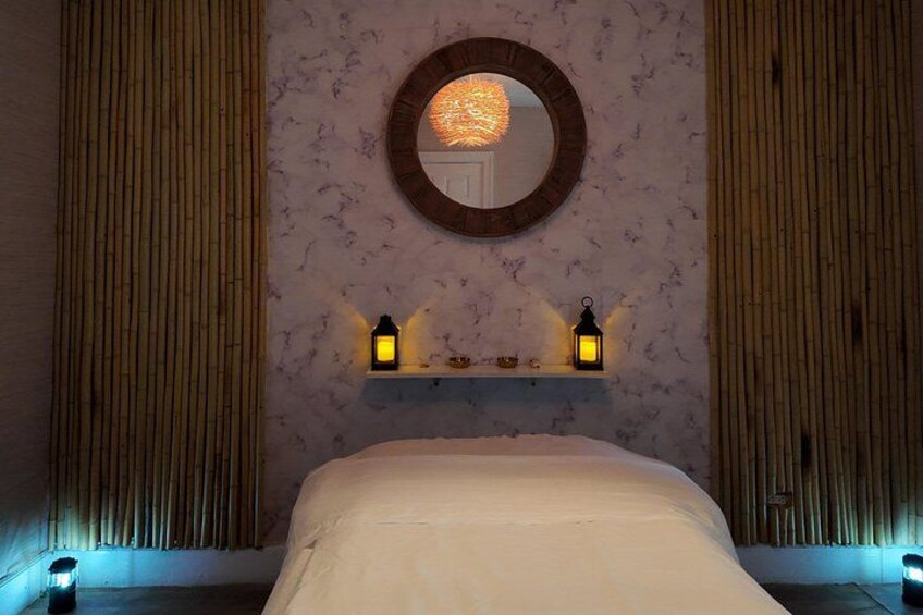 A bedroom with a bed, a round mirror, and two wall-mounted lanterns. 3