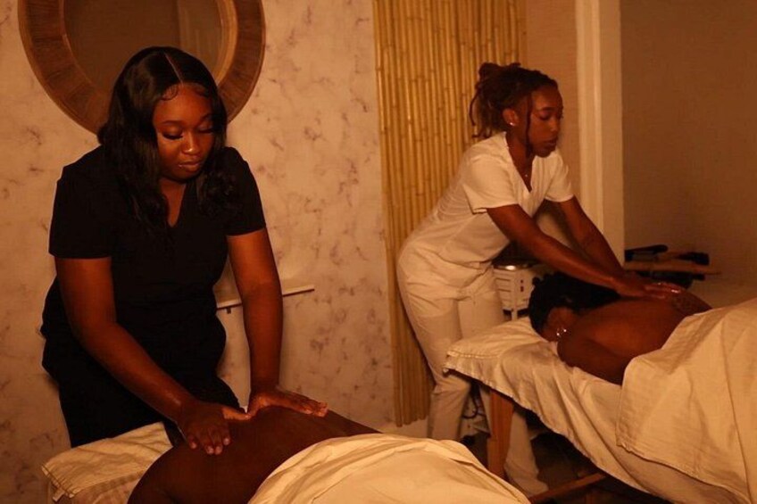 A massage therapy session in a room with a patterned wall and a circular mirror. 2