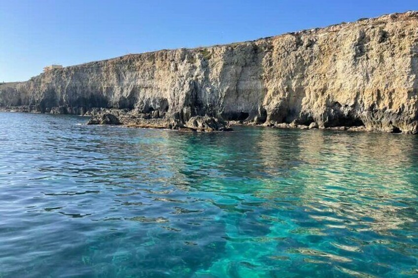 A coastal cliff with clear turquoise water. 1