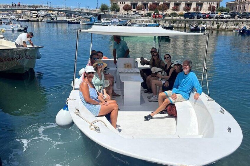 A group of people on a small boat in a marina with other boats and a bridge in the background. 5