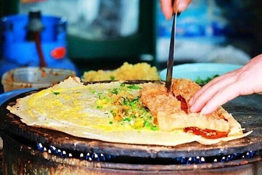A person cutting a fried egg on a griddle. 1