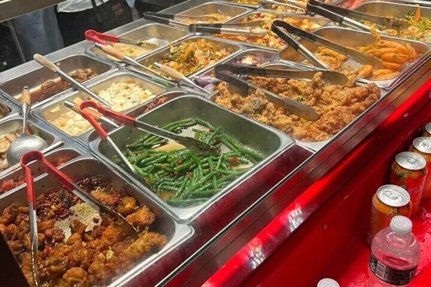 A buffet with various food items in metal containers, including fried chicken, green beans, and other dishes. 2