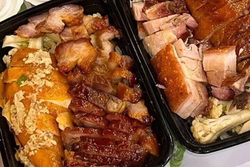 A meal with roasted pork and vegetables in a black container. 5