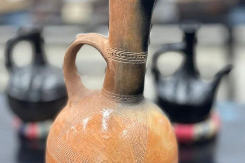 Primer plano de una jarra de cerámica con asa, rodeada de objetos similares. 5