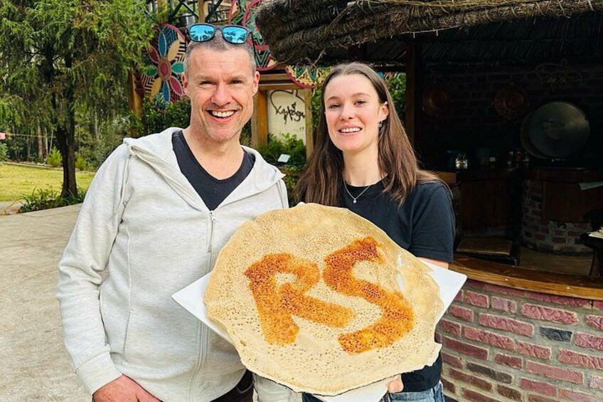 Dos personas sosteniendo una crepe grande con la letra 'R'. 2