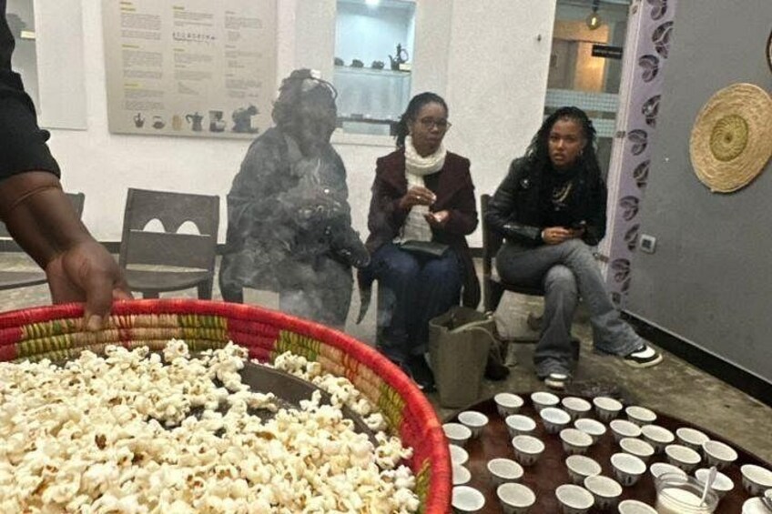 Una persona sirviendo palomitas de maíz a tres personas sentadas en una habitación con pared estampada. 4
