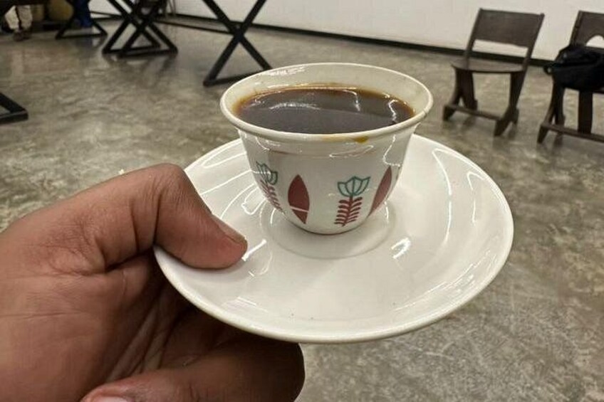 Una mano sosteniendo una taza de café sobre un plato. 3