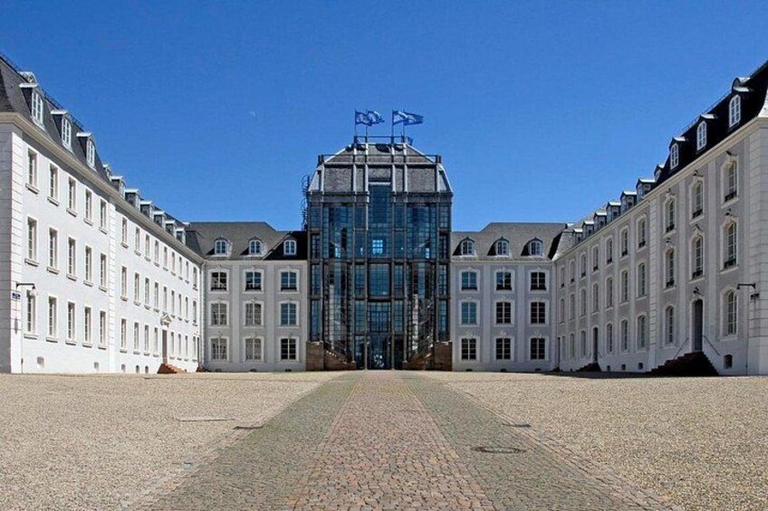 Un grand bâtiment blanc à la façade de verre, entouré d’autres bâtiments blancs dotés de nombreuses fenêtres. 2