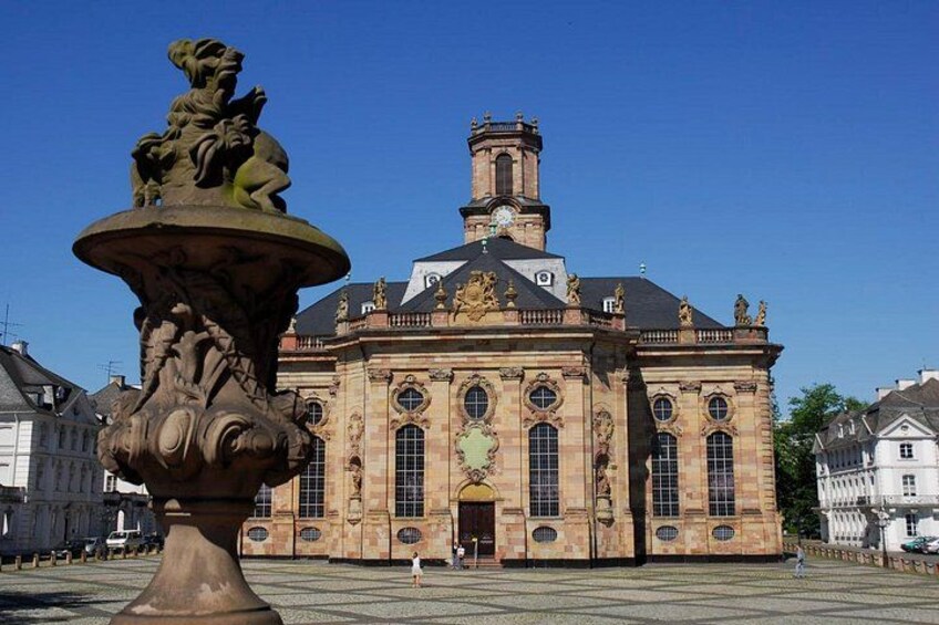 Un bâtiment historique doté d’une grande tour horlogère centrale, de sculptures élaborées et d’une fontaine en premier plan. 4