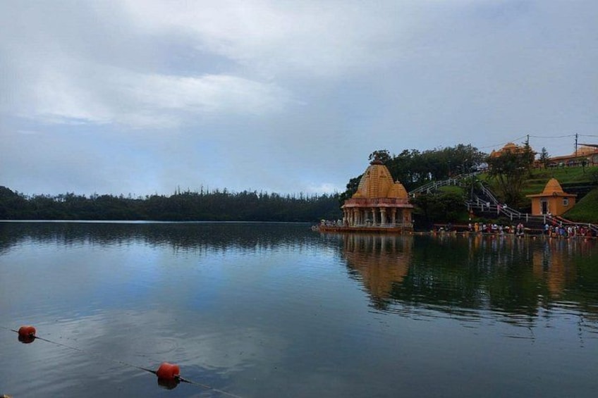 A calm lake with a temple on an island, surrounded by trees and a cloudy sky. 2