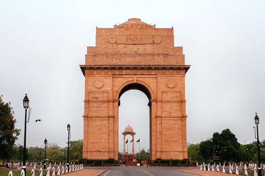 India Gate, et stort bueformet monument, med en kuppelstruktur i baggrunden. 5